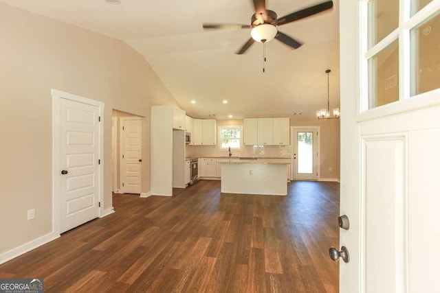 kitchen featuring a center island, dark hardwood / wood-style floors, pendant lighting, vaulted ceiling, and white cabinets