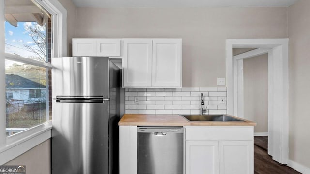 kitchen with sink, stainless steel appliances, wood counters, backsplash, and white cabinets