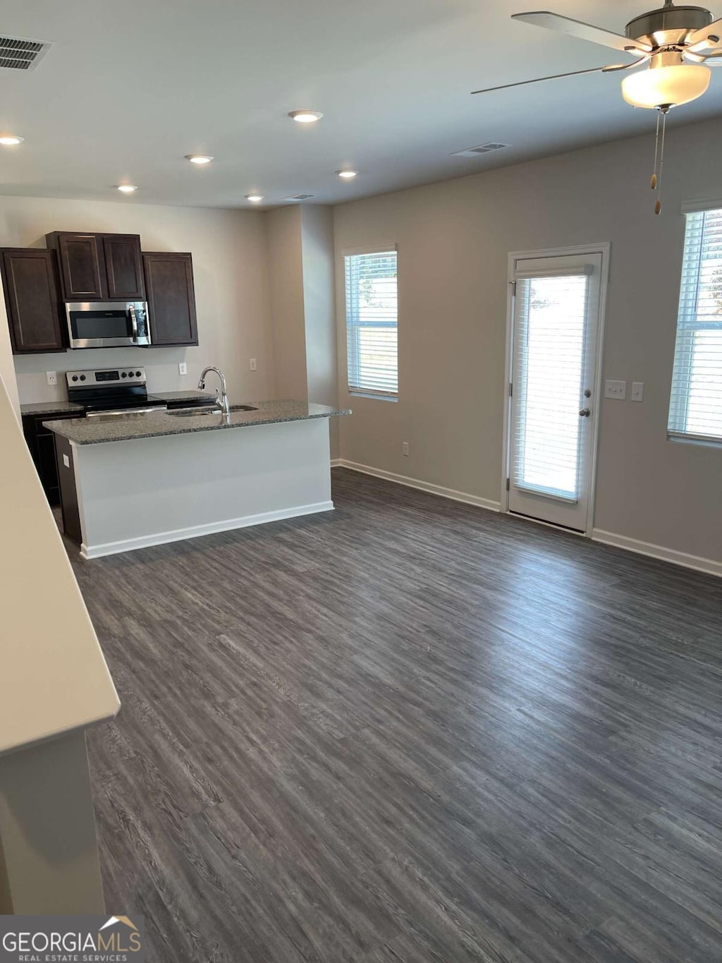 kitchen with sink, stainless steel appliances, dark hardwood / wood-style floors, an island with sink, and dark brown cabinets