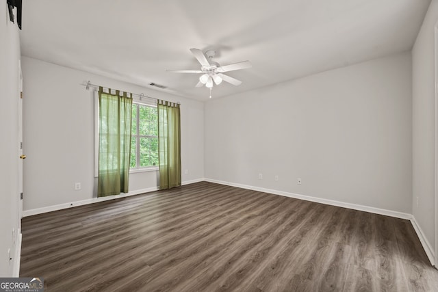 empty room featuring dark wood finished floors, visible vents, ceiling fan, and baseboards