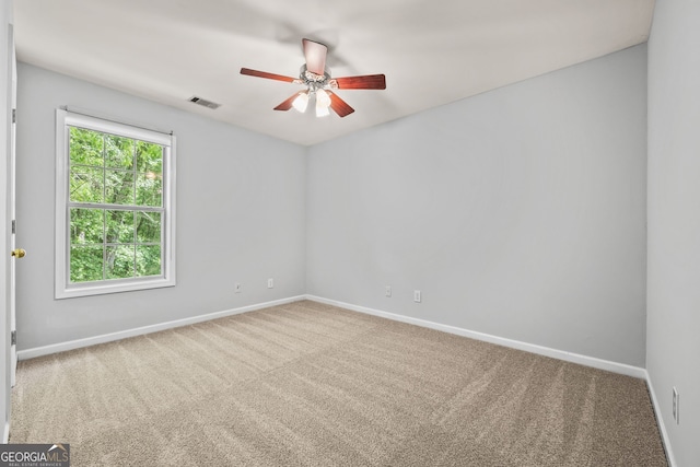 carpeted spare room featuring baseboards, a ceiling fan, and visible vents