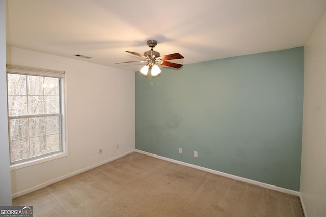 unfurnished room featuring a healthy amount of sunlight, baseboards, visible vents, and light colored carpet