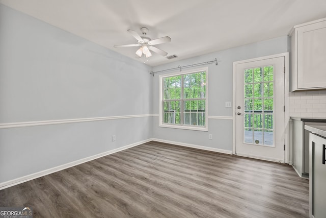 interior space with wood finished floors, a fireplace, baseboards, visible vents, and a ceiling fan