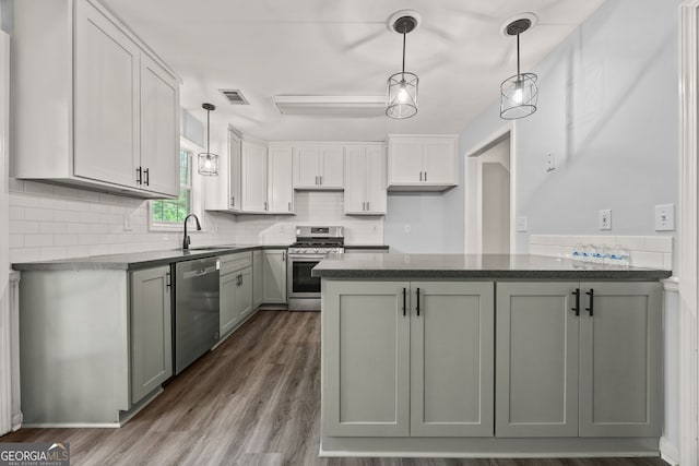 kitchen with pendant lighting, a sink, visible vents, stainless steel appliances, and a peninsula