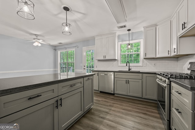 kitchen with a sink, ceiling fan, dark countertops, stainless steel appliances, and visible vents