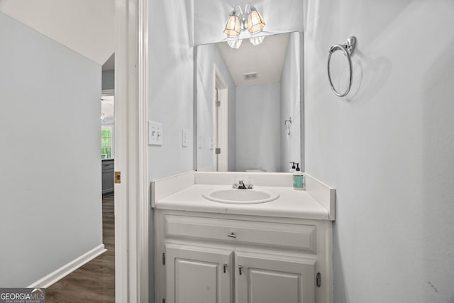 bathroom with wood finished floors, vanity, visible vents, and baseboards