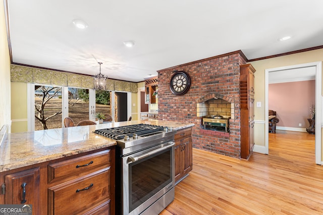 kitchen with light stone countertops, hanging light fixtures, light hardwood / wood-style flooring, high end stove, and ornamental molding