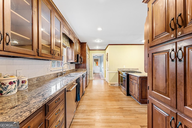 kitchen with sink, light hardwood / wood-style flooring, appliances with stainless steel finishes, tasteful backsplash, and light stone counters