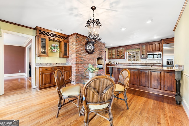 dining room with light hardwood / wood-style floors, a notable chandelier, ornamental molding, and sink