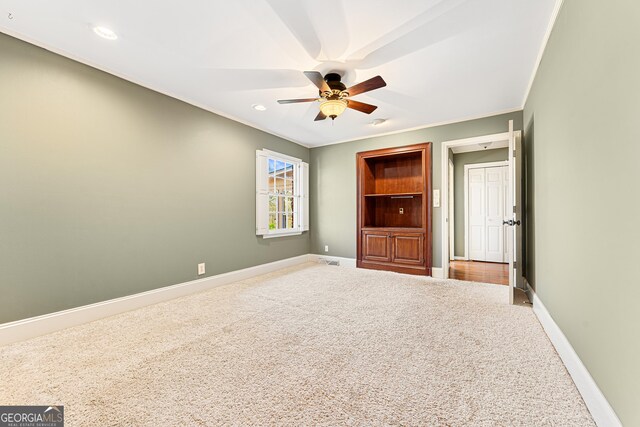 carpeted spare room featuring ceiling fan and crown molding