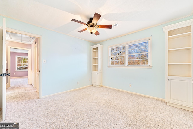 unfurnished room with light carpet, ceiling fan, and crown molding