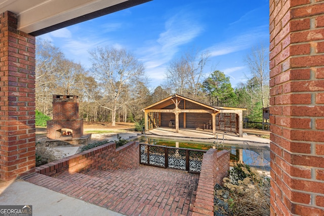 view of patio with a gazebo, a swimming pool, and an outdoor brick fireplace