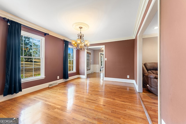 spare room featuring hardwood / wood-style floors, crown molding, and a notable chandelier