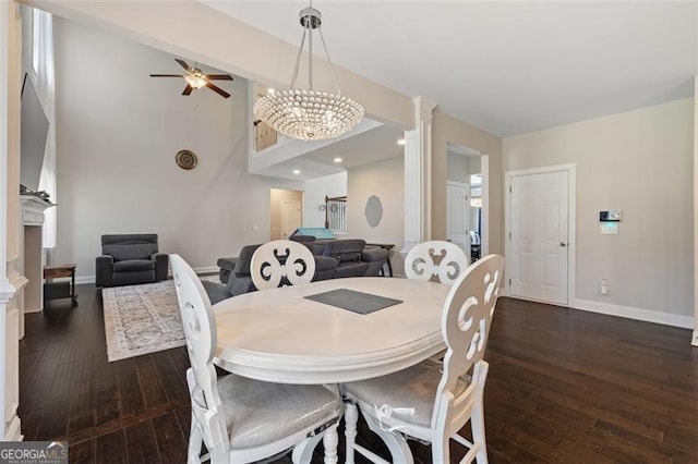 dining space featuring a fireplace, ceiling fan with notable chandelier, and dark hardwood / wood-style floors