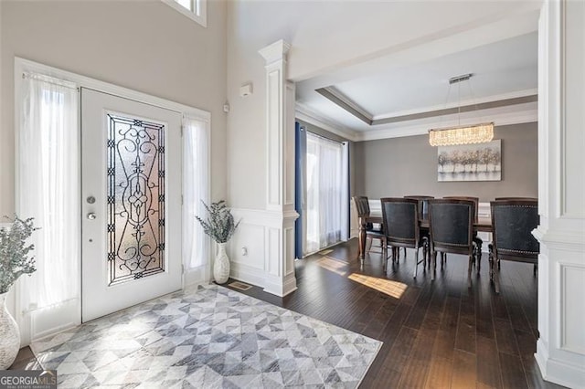 entryway featuring a chandelier, ornamental molding, a healthy amount of sunlight, and wood-type flooring