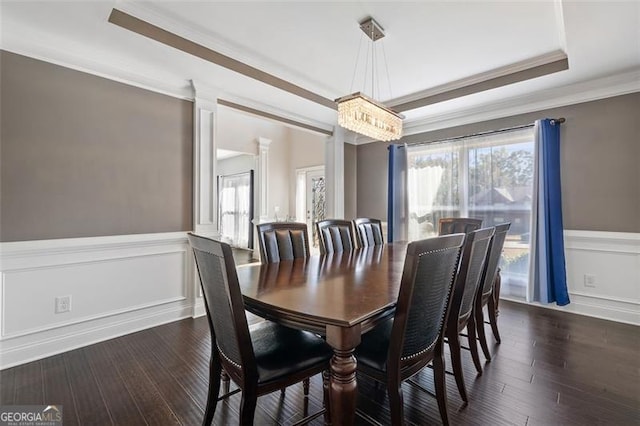 dining area featuring dark hardwood / wood-style flooring, a raised ceiling, crown molding, and a notable chandelier