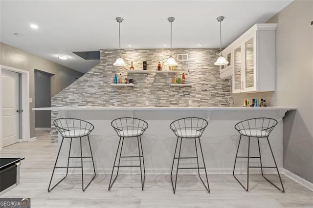 bar with pendant lighting, light hardwood / wood-style floors, and white cabinetry