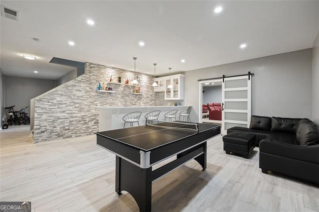 recreation room with light wood-type flooring and a barn door