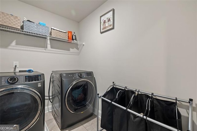 laundry area featuring washing machine and clothes dryer and light tile patterned floors