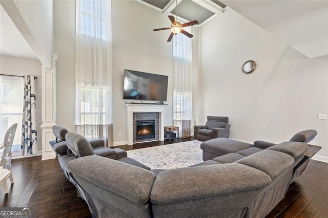 living room with a wealth of natural light, a towering ceiling, and dark wood-type flooring