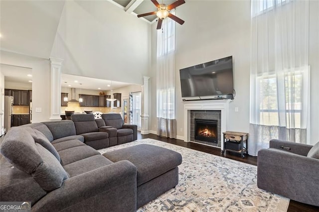 living room featuring a towering ceiling, hardwood / wood-style flooring, ceiling fan, and a healthy amount of sunlight