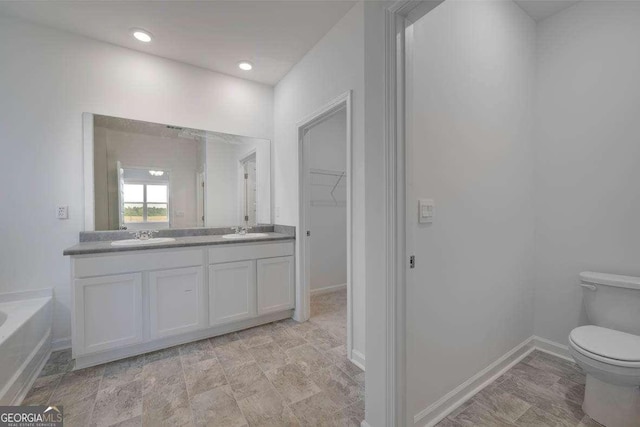 bathroom with vanity, toilet, and a tub to relax in