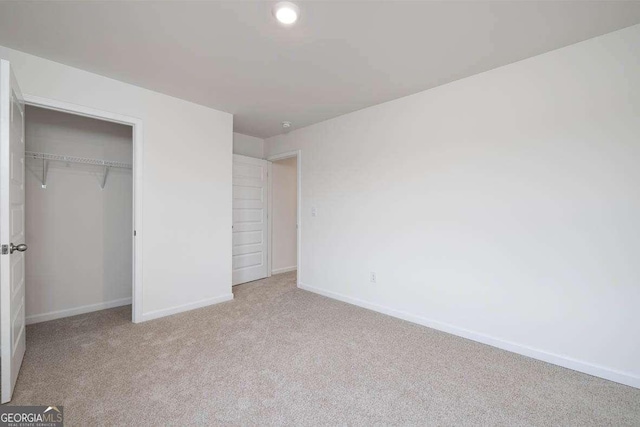 unfurnished bedroom with light colored carpet and a closet