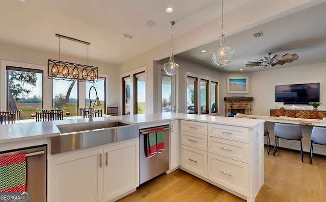 kitchen with ceiling fan, sink, hanging light fixtures, white cabinets, and light wood-type flooring