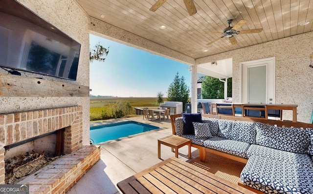 view of pool with an outdoor living space with a fireplace, a patio area, and ceiling fan