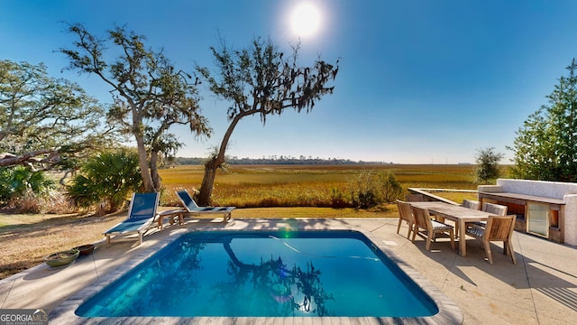 view of swimming pool featuring a rural view and a patio