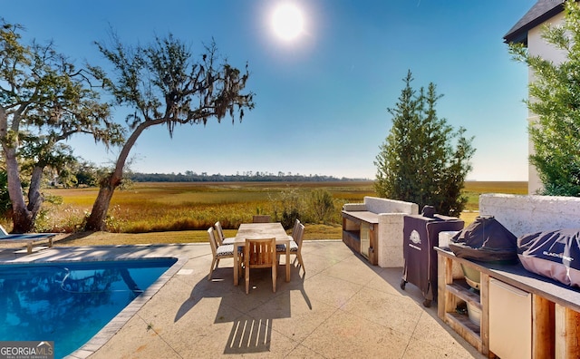 view of swimming pool with a patio area and a rural view