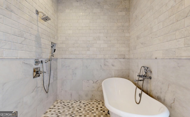 bathroom with tile patterned flooring, a bathtub, and tile walls