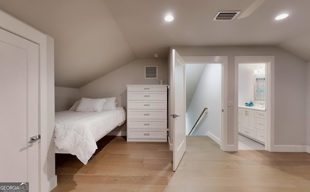 bedroom featuring light wood-type flooring, connected bathroom, and lofted ceiling