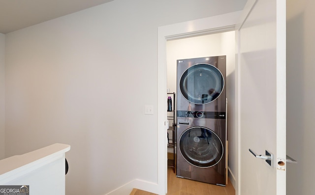 washroom with stacked washer / drying machine and light wood-type flooring