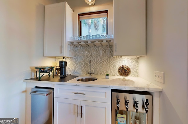 bar with wine cooler, light stone countertops, sink, and white cabinets