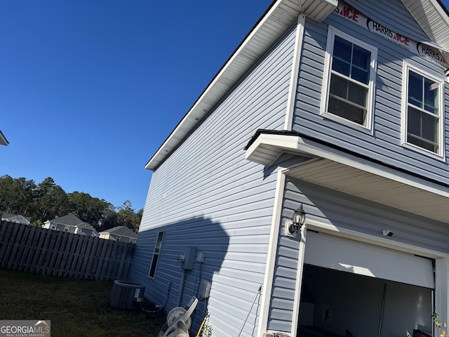 view of side of property featuring central air condition unit and a garage