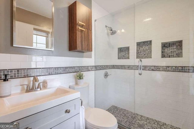 bathroom featuring vanity, toilet, a shower with shower door, and tile walls