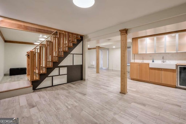 basement with light wood-type flooring, sink, and beverage cooler