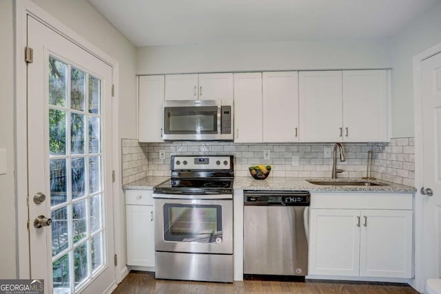 kitchen featuring hardwood / wood-style floors, white cabinets, sink, appliances with stainless steel finishes, and light stone counters