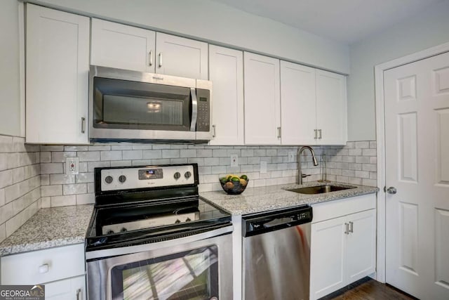 kitchen featuring white cabinets, sink, decorative backsplash, light stone countertops, and appliances with stainless steel finishes