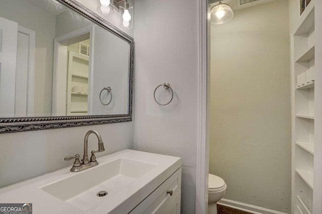 bathroom with built in features, vanity, and toilet