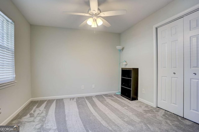 unfurnished bedroom with a closet, light colored carpet, and ceiling fan