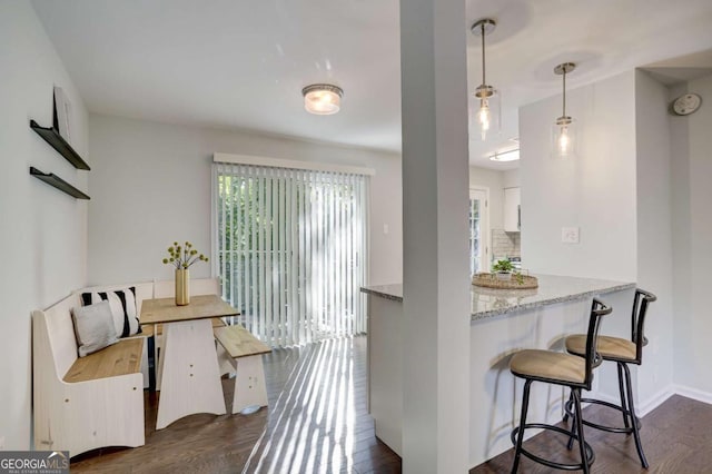 kitchen featuring dark hardwood / wood-style floors, light stone counters, white cabinetry, and hanging light fixtures