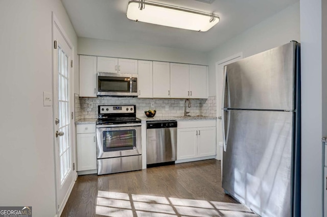 kitchen featuring white cabinetry, sink, tasteful backsplash, appliances with stainless steel finishes, and hardwood / wood-style flooring