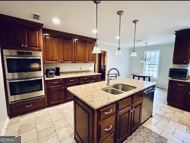 kitchen featuring visible vents, pendant lighting, an island with sink, a sink, and appliances with stainless steel finishes