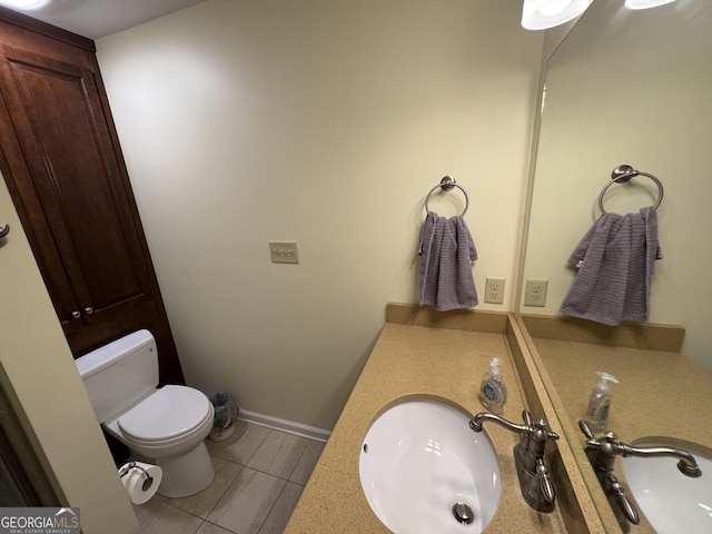 half bathroom featuring a sink, baseboards, and toilet