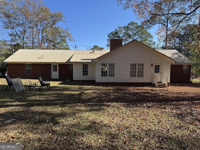 back of property featuring a chimney and metal roof