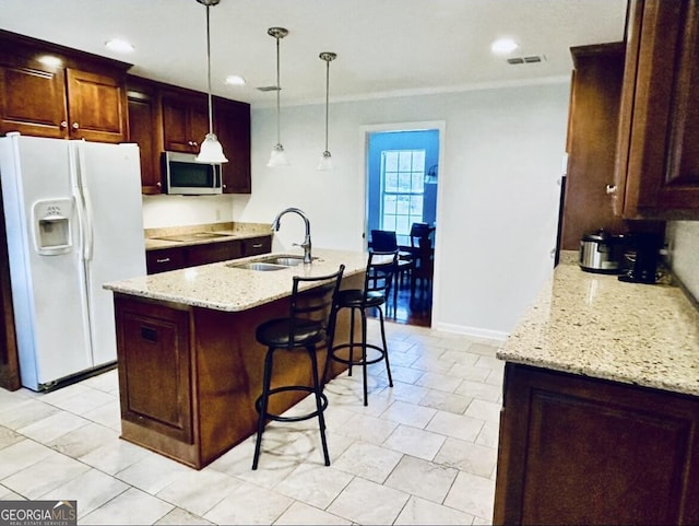 kitchen featuring visible vents, a sink, stainless steel microwave, white refrigerator with ice dispenser, and black electric cooktop