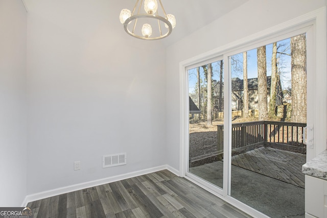 empty room with dark hardwood / wood-style floors and a notable chandelier