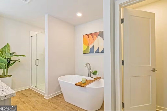 bathroom featuring plus walk in shower and hardwood / wood-style floors